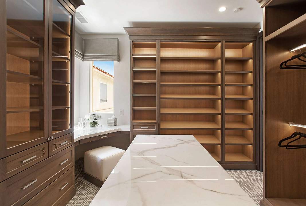 closet with lots of shelving and a corner makeup desk in brown